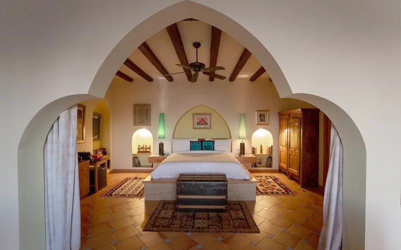 Pharaoh bedroom framed by a pointed arch, with beamed ceiling and kilim rugs