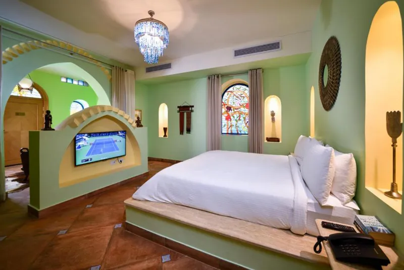 Sphinx bedroom with a raised bed, chandelier and stained-glass window