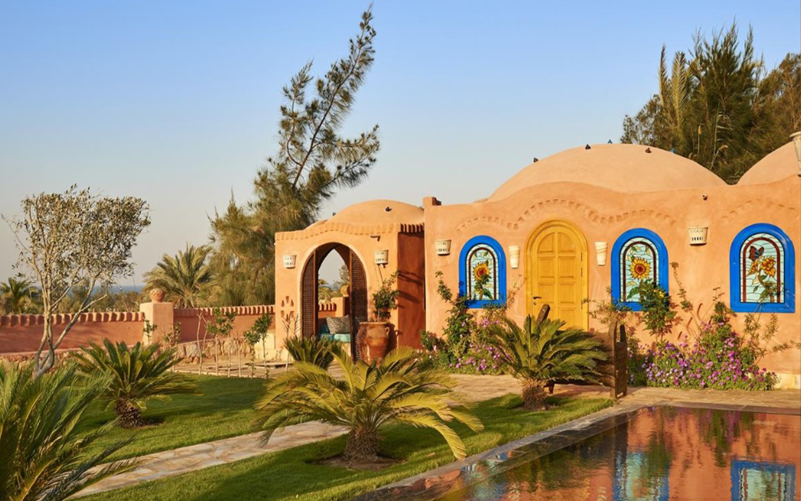 Close view of domed rooms with stained-glass arched windows and a garden.