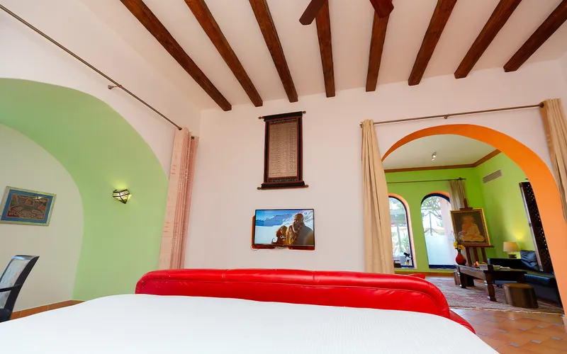 Beamed bedroom opening through an orange arch into a sitting room